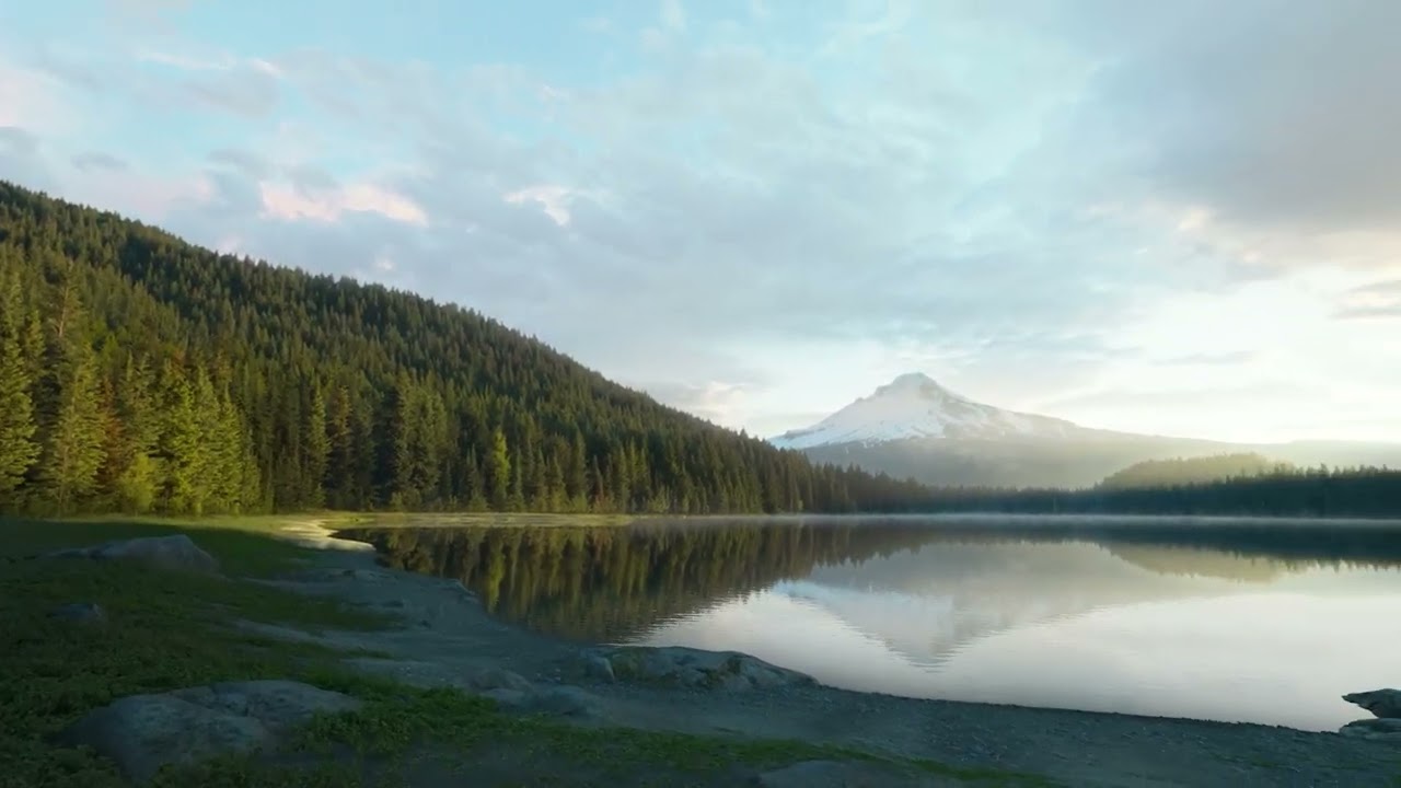 A serene lake nestled amidst majestic mountains and lush trees in front of Mount Hood, viewed through the Apple Vision Pro virtual reality headset.